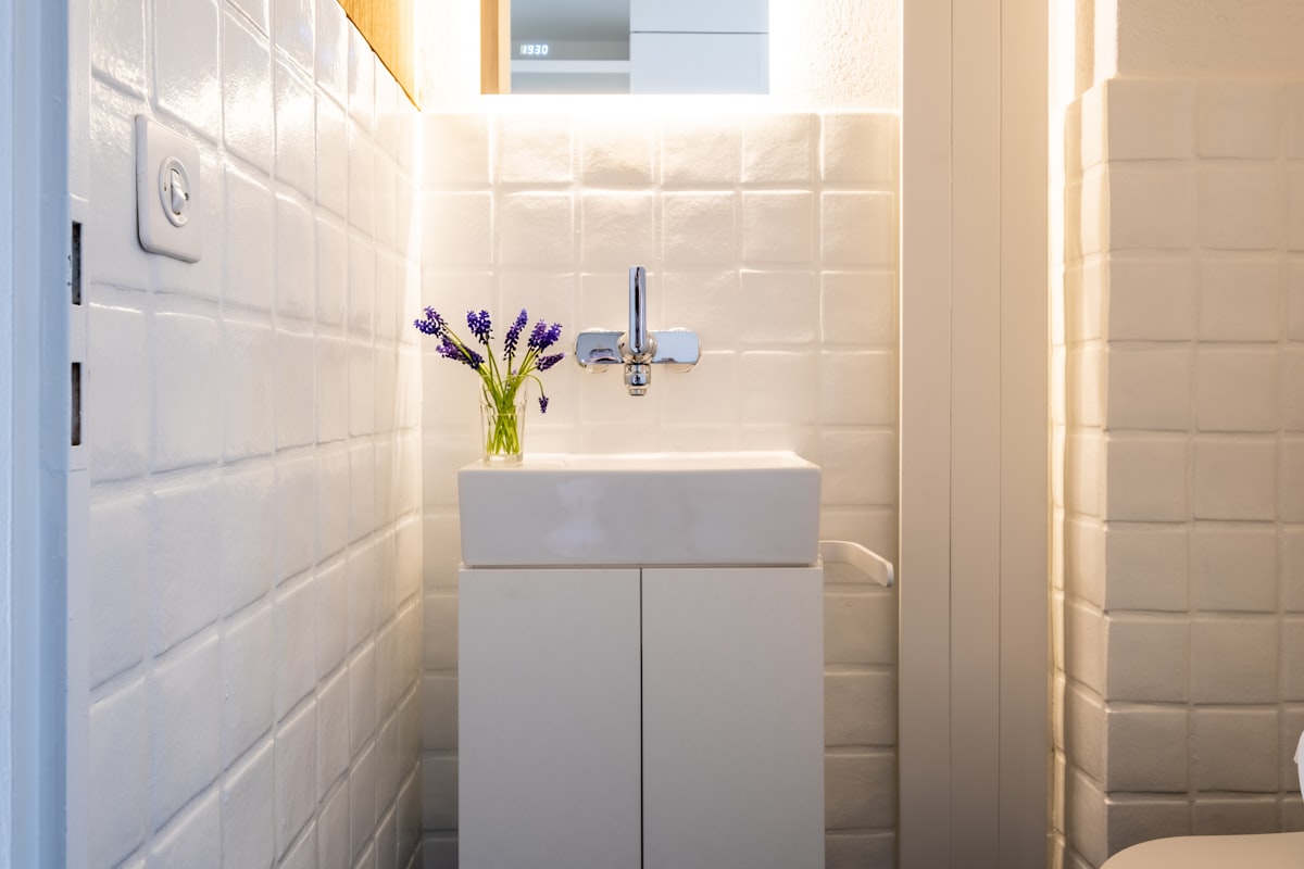 A clean white subway-tiled Austin bathroom with natural light, cleaning spray bottle on the edge of the bathtub